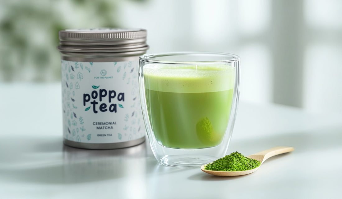 hot matcha latte in a clear cup next to a vibrant green matcha powder on a bamboo spoon