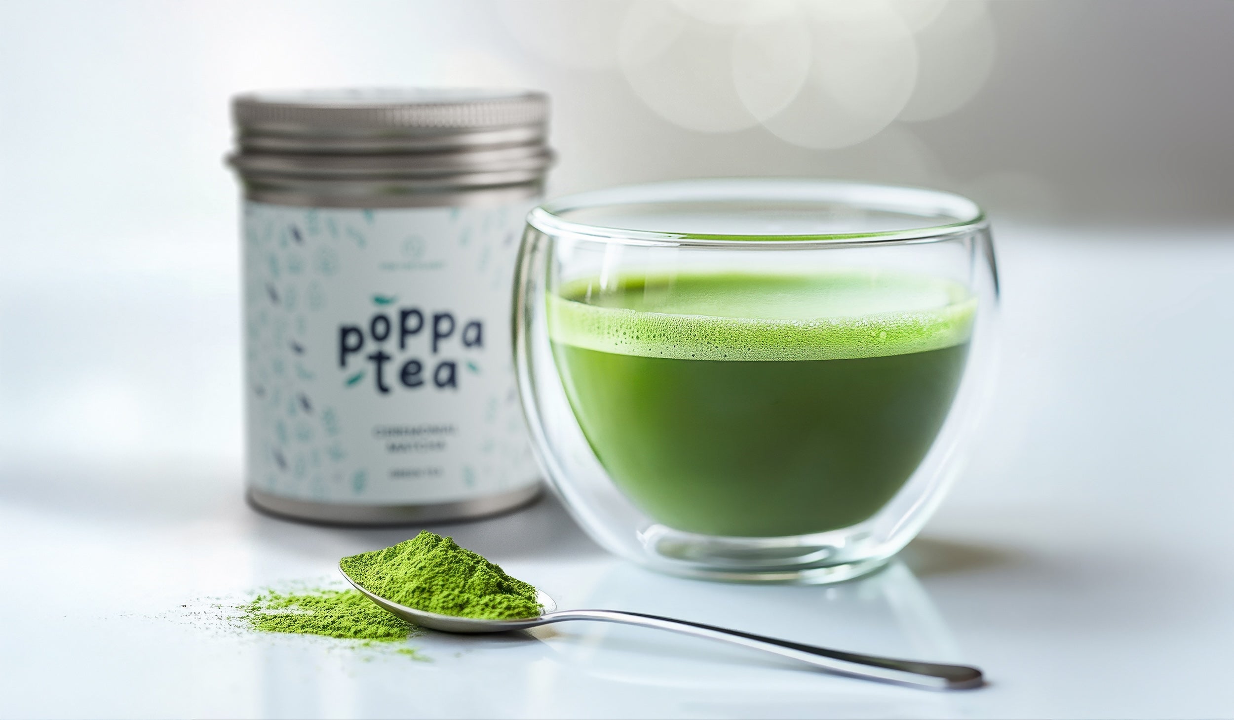 Quick Matcha Latte in a clear cup next to some loose matcha tea powder on a spoon