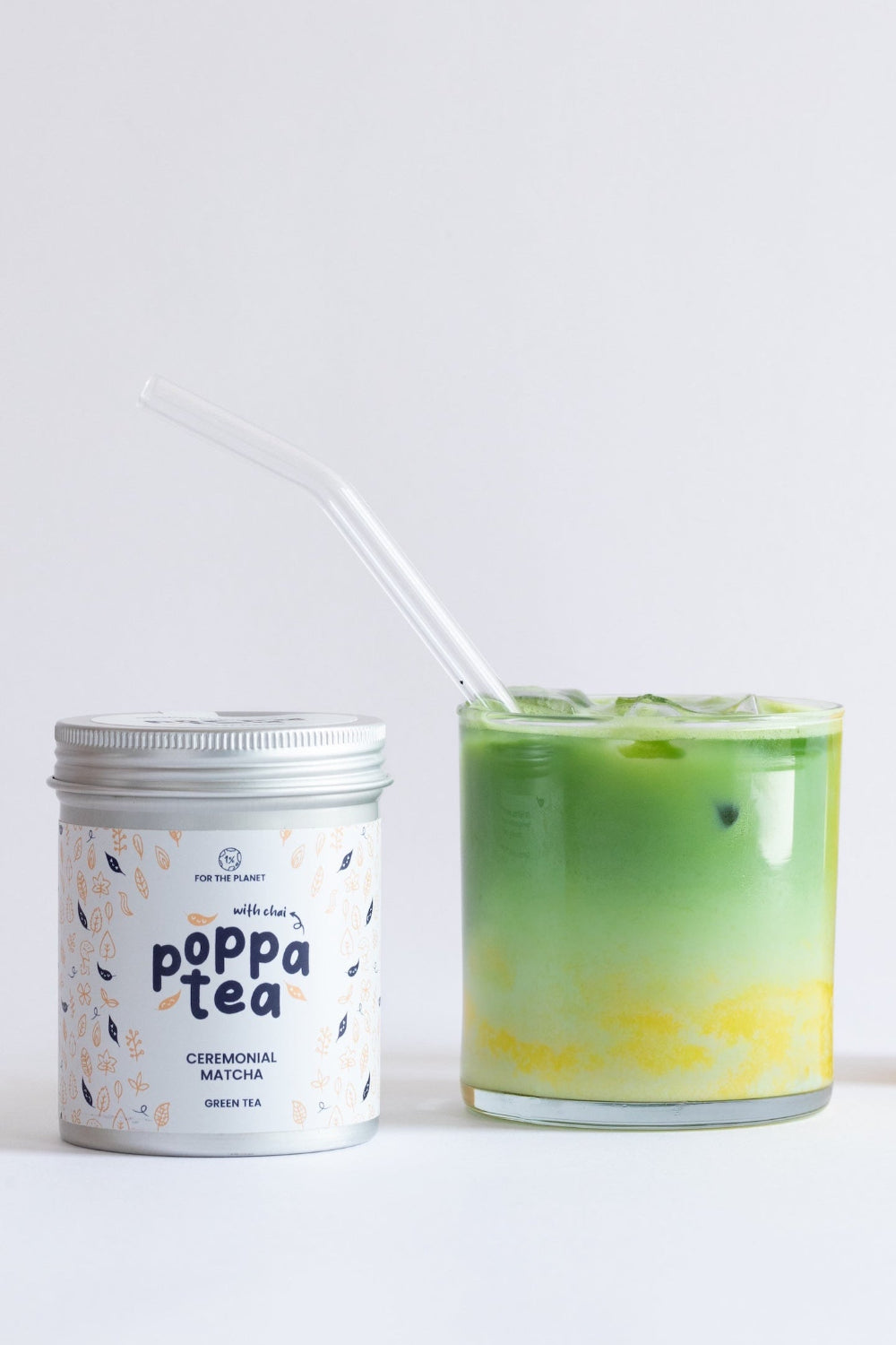 Three items from Poppa Tea on a clean white background: a silver-lidded white jar labeled 'matcha with chai', a green-and-yellow layered iced drink with a clear straw, and a tall squeeze bottle filled with yellow and white marbled liquid.