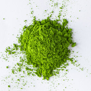 vibrant green first harvest matcha powder in a pile and on a white background