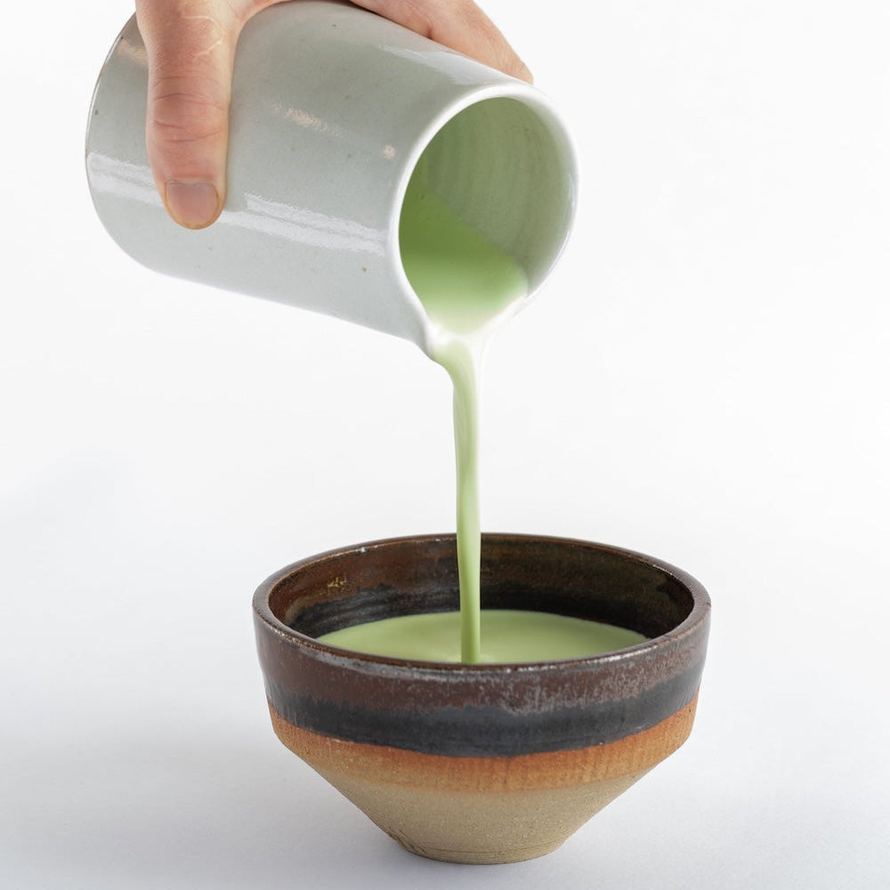 foamy chai matcha latte being poured into a bowl