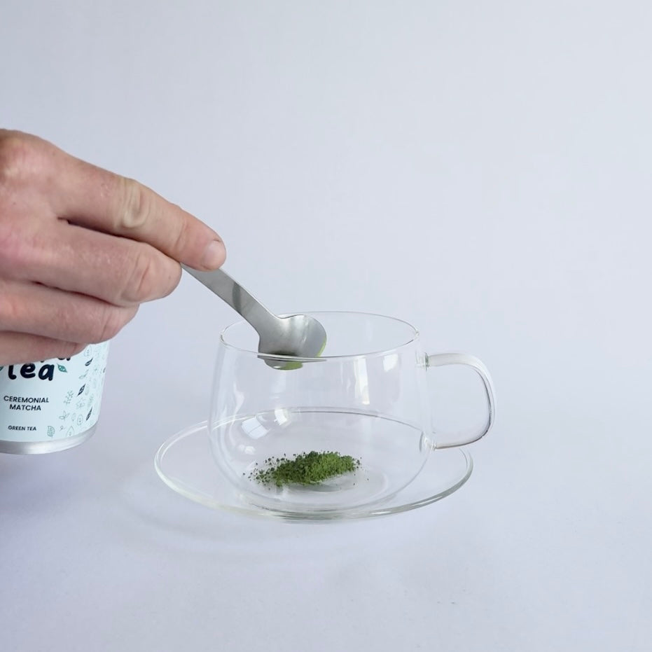 half a level teaspoon of PoppaTea matcha being put into a clear cup
