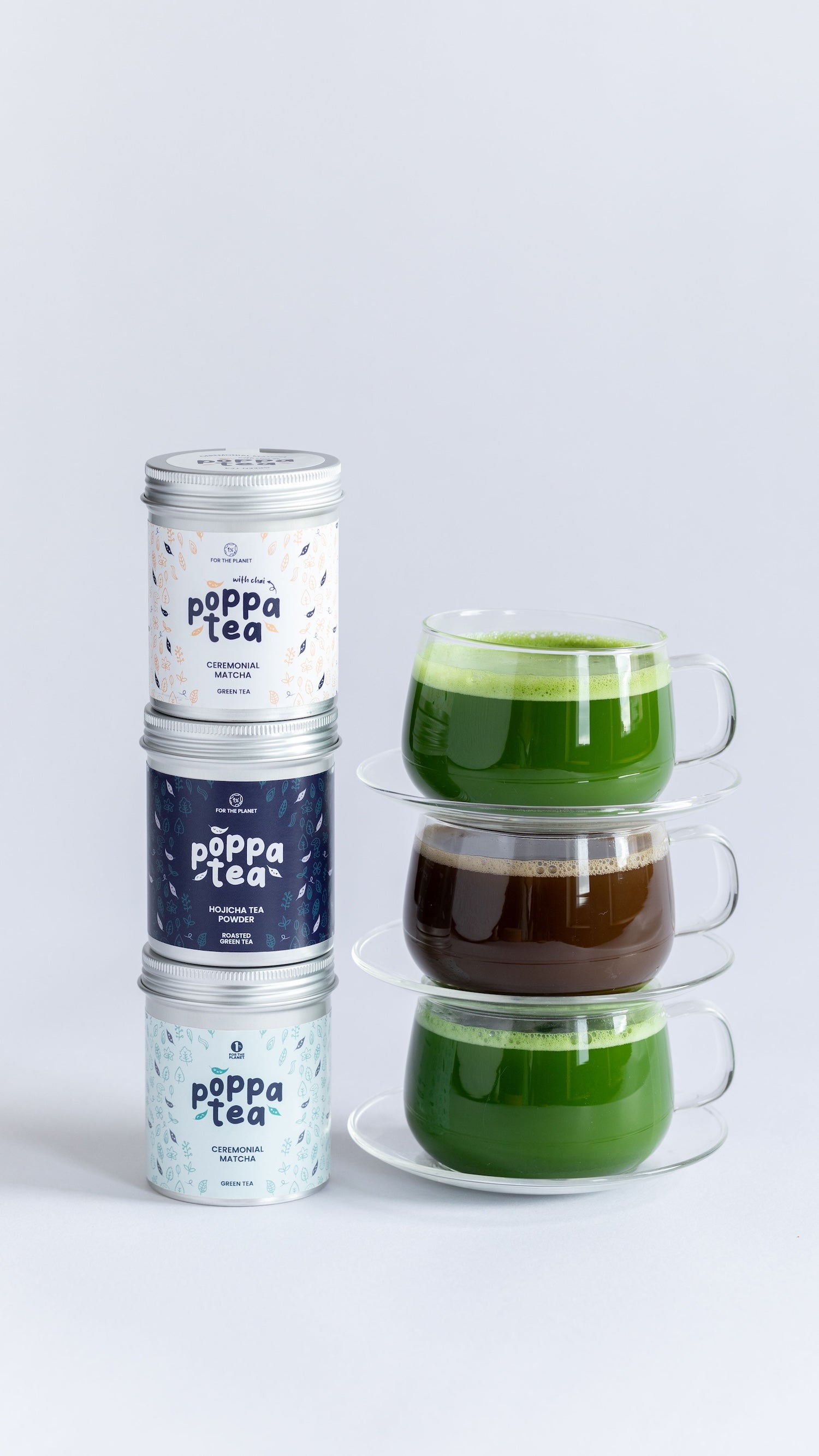 Stack of glass cups with green and brown liquids and matching tea tins on a light gray background