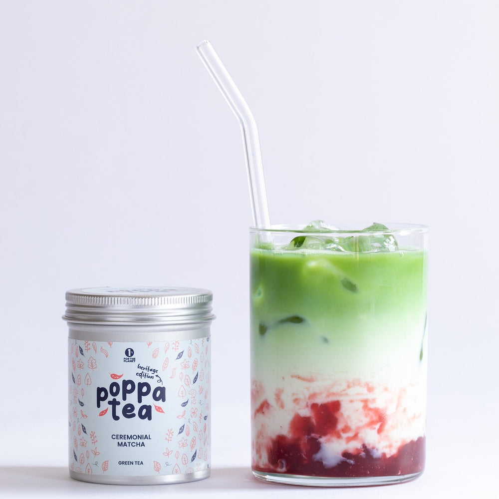 Poppa Tea matcha heritage edition canister with a glass of strawberry matcha latte on a white background