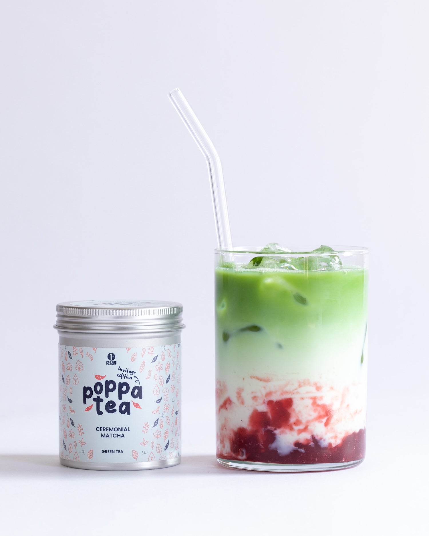 Poppa Tea matcha heritage edition canister with a glass of strawberry matcha latte on a white background