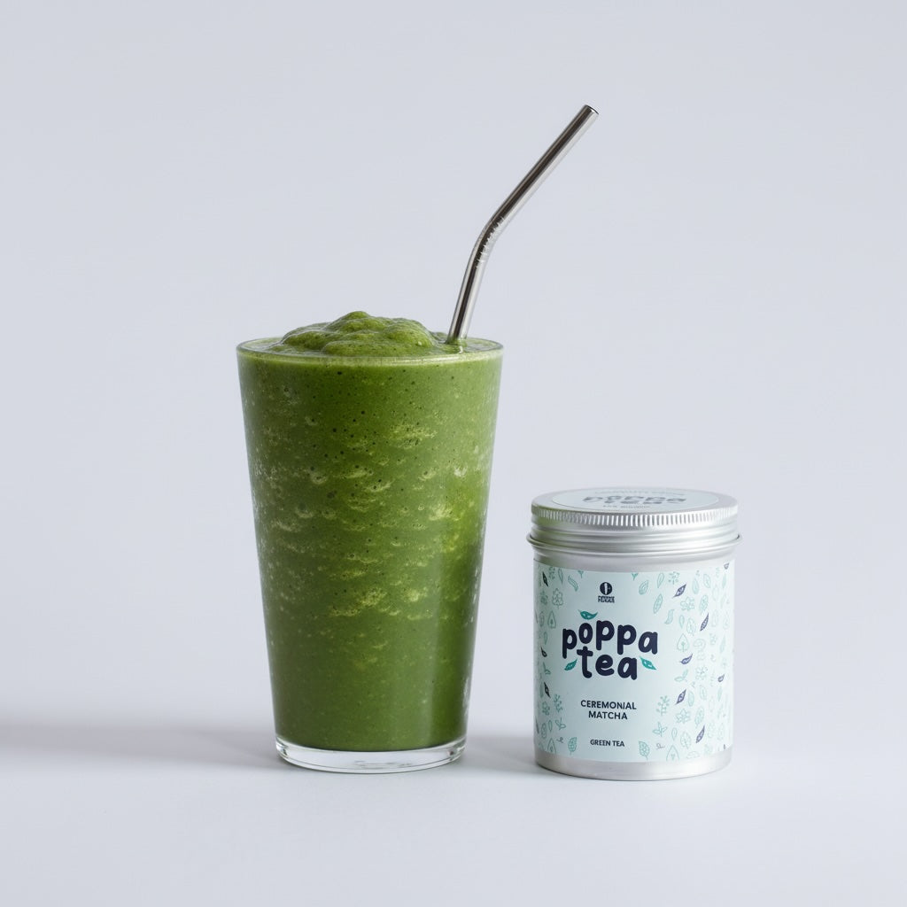 matcha tea smoothie in a clear glass cup with a straw and next to a tin of PoppaTea matcha