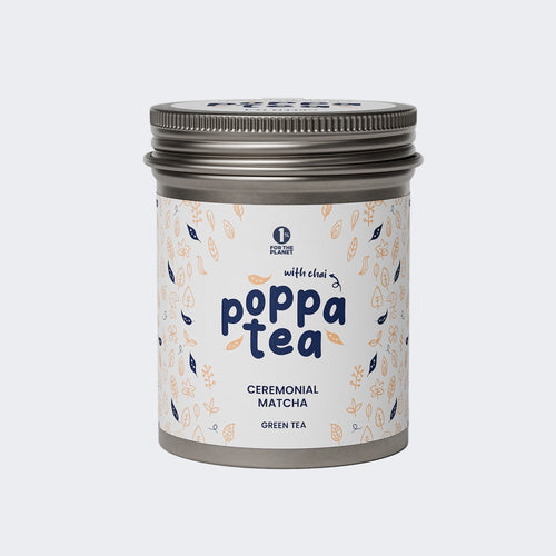 A tin container of Poppatea Ceremonial Matcha Green Tea with Chai, featuring a white label with floral and tea leaf illustrations.