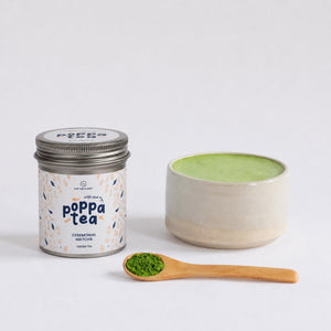 Image of hot matcha latte in a matcha bowl with a spoon of matcha tea with chai next to the cup