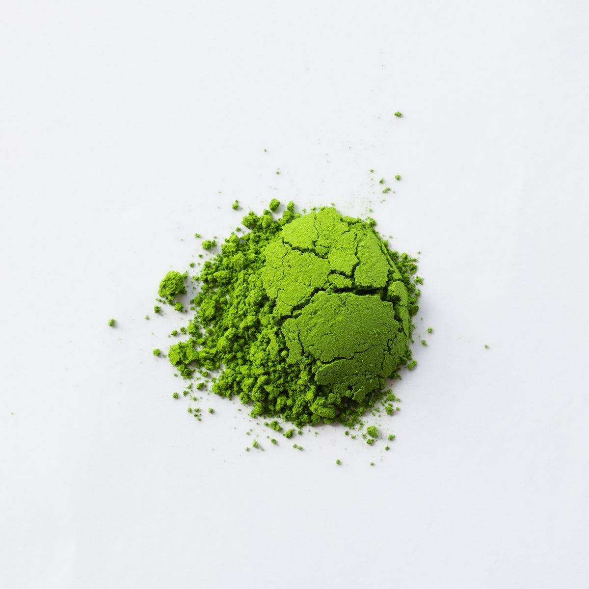 A small mound of bright green matcha powder photographed on a clean white background.
